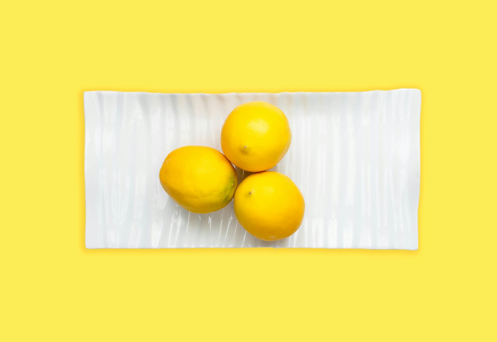 Fresh lemons on white plate against yellow background, symbolizing natural intimacy and authentic connection
