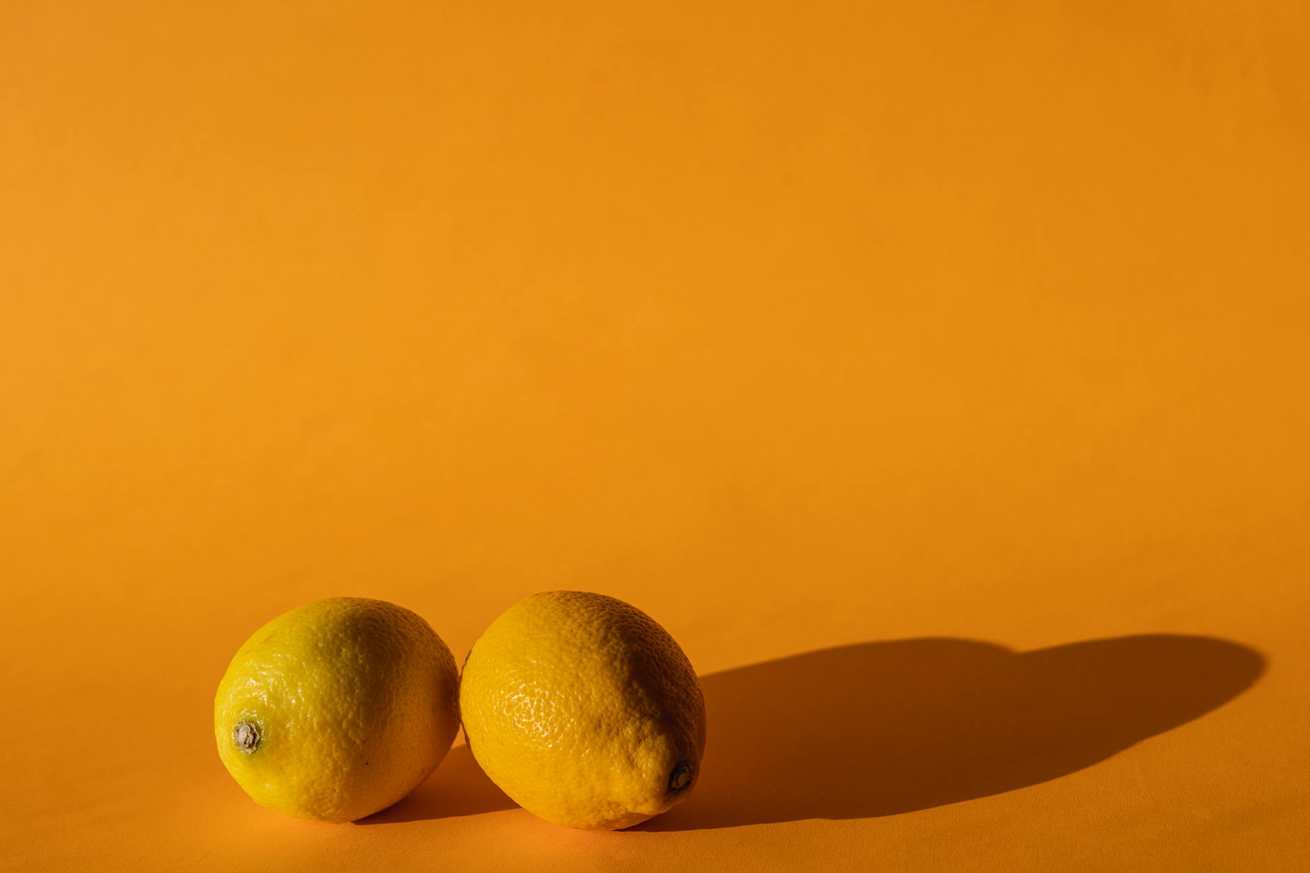 Bright yellow lemons arranged on a pastel green background, representing fresh and balanced approaches to pleasure